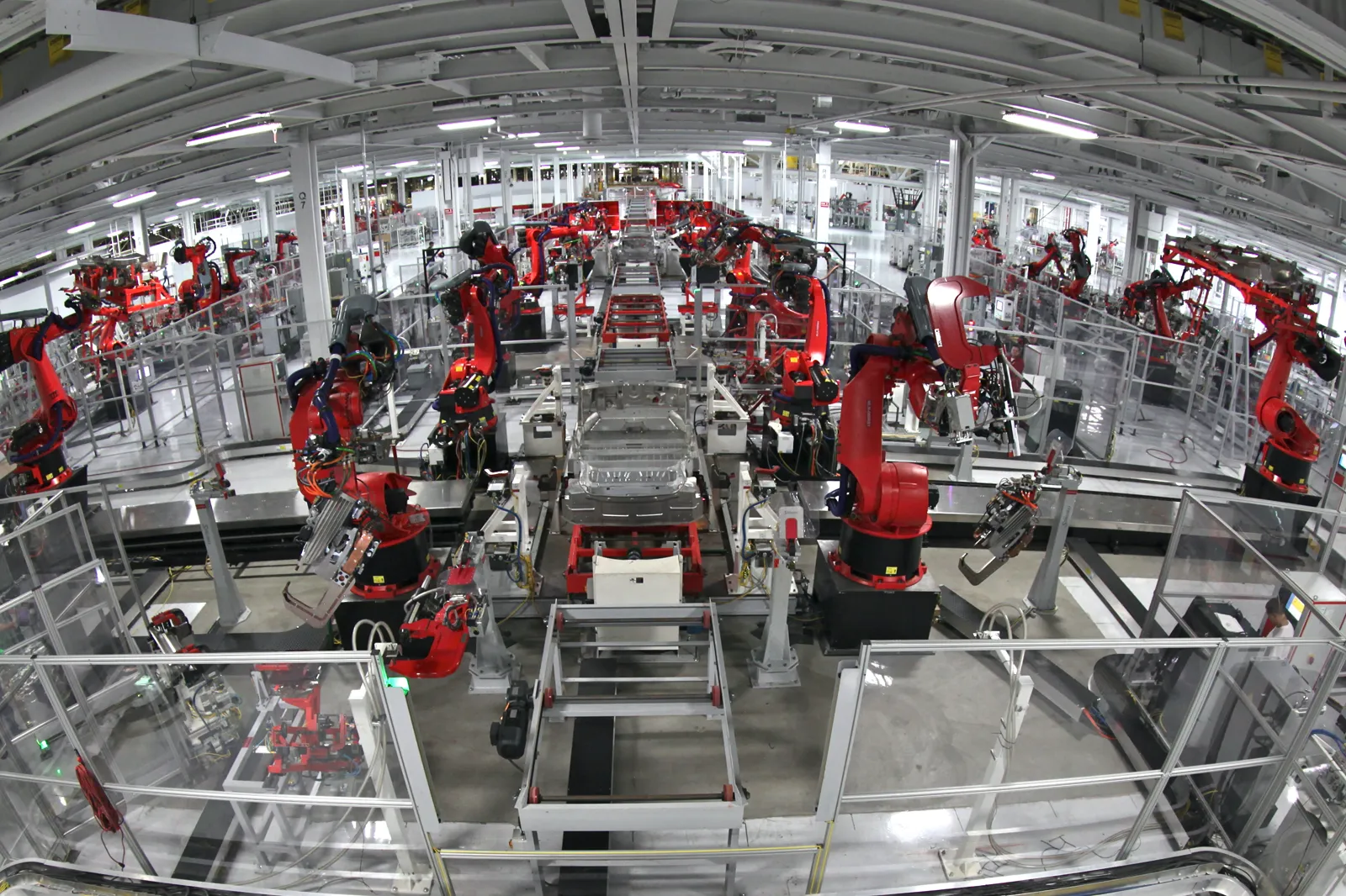 Rows of red welding robots around car bodies in the Fremont factory