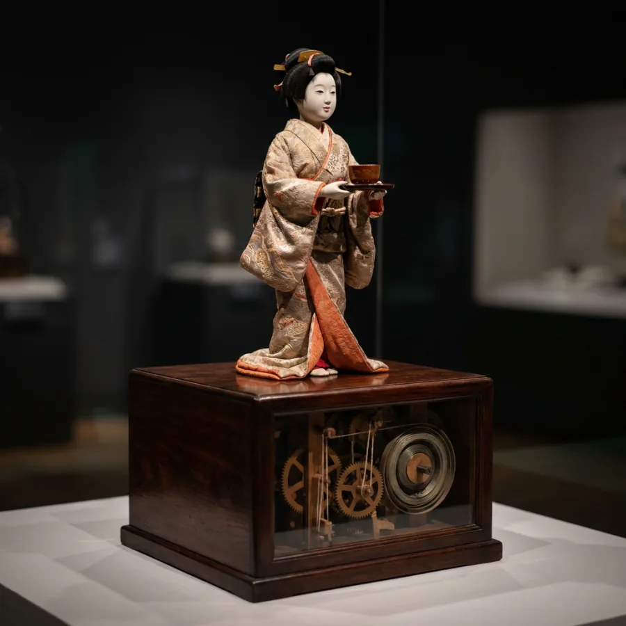 An Edo-period tea-serving doll — whalebone spring, wooden cams. The ancestor.