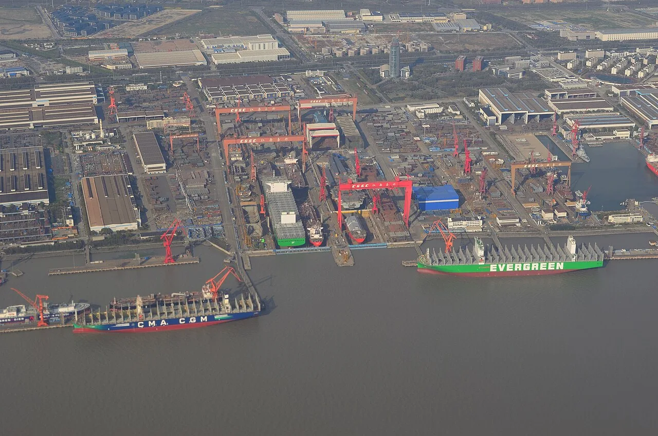 Aerial view of Jiangnan Shipyard with red gantry cranes and two large container ships at the quay