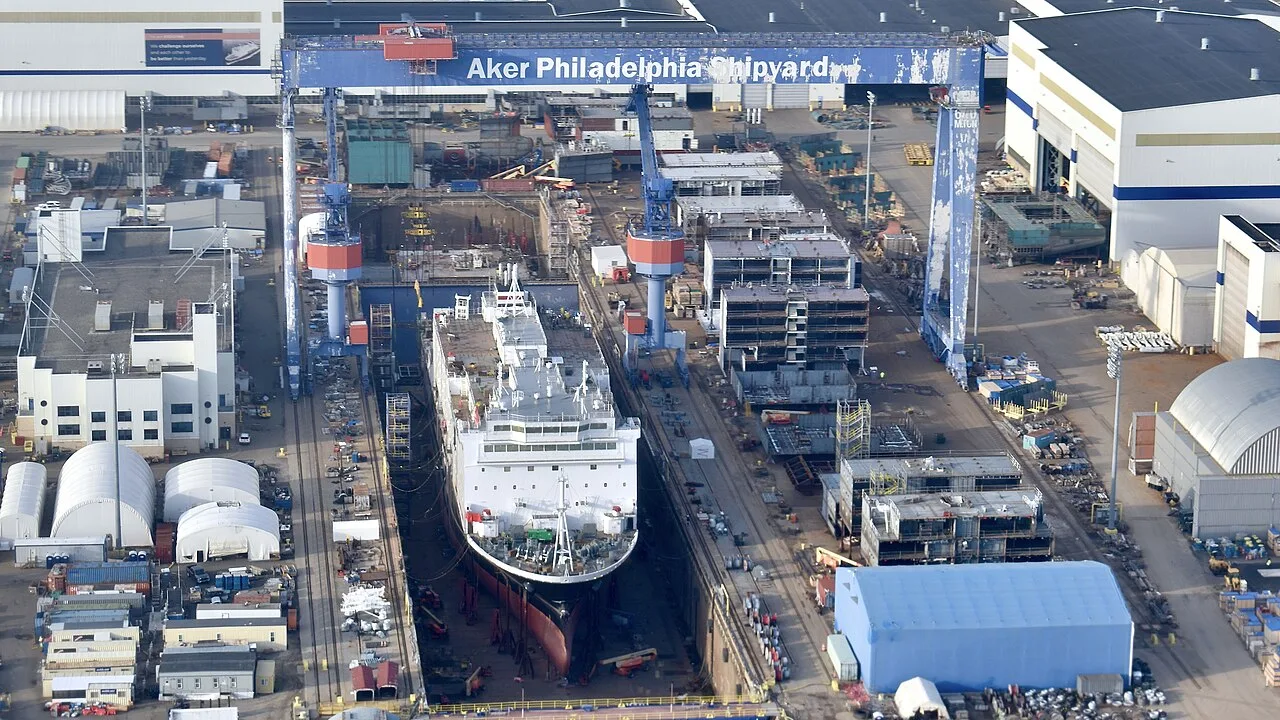 Aerial view of Philly Shipyard with a large white ship under construction in the dry dock