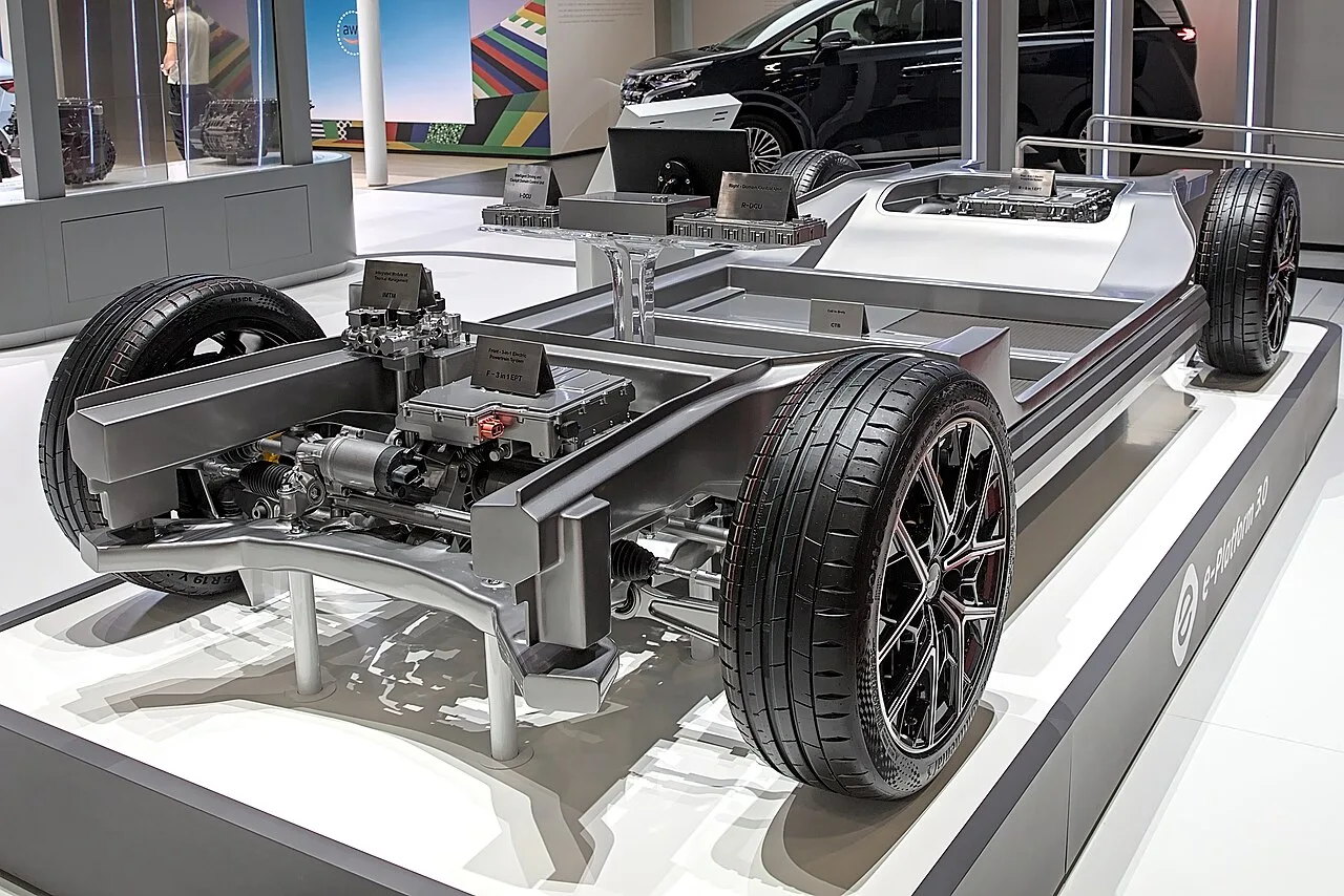 A bare BYD electric car chassis with wheels, motors and electronics on a show stand