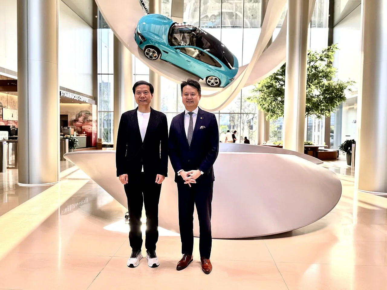 Lei Jun, left, standing beside WIPO Director General Daren Tang under a suspended Xiaomi car